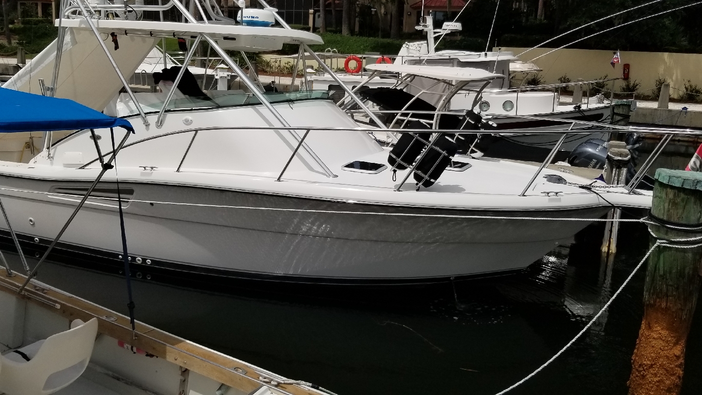 A white sportfisher tied up at a marina with clean topsides